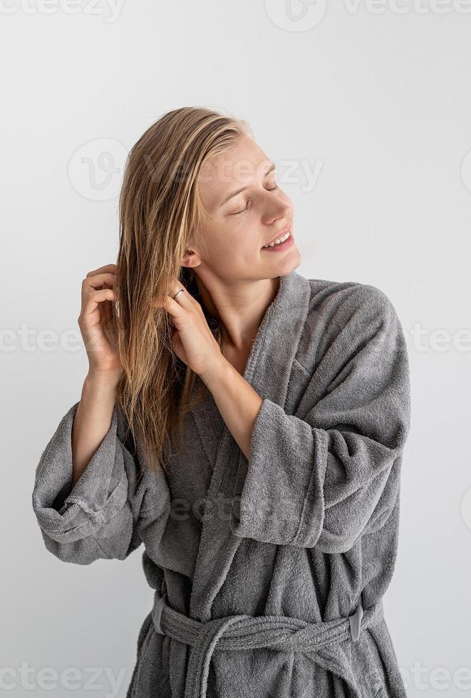 heureuse jeune femme appliquant un masque capillaire dans la salle de bain photo