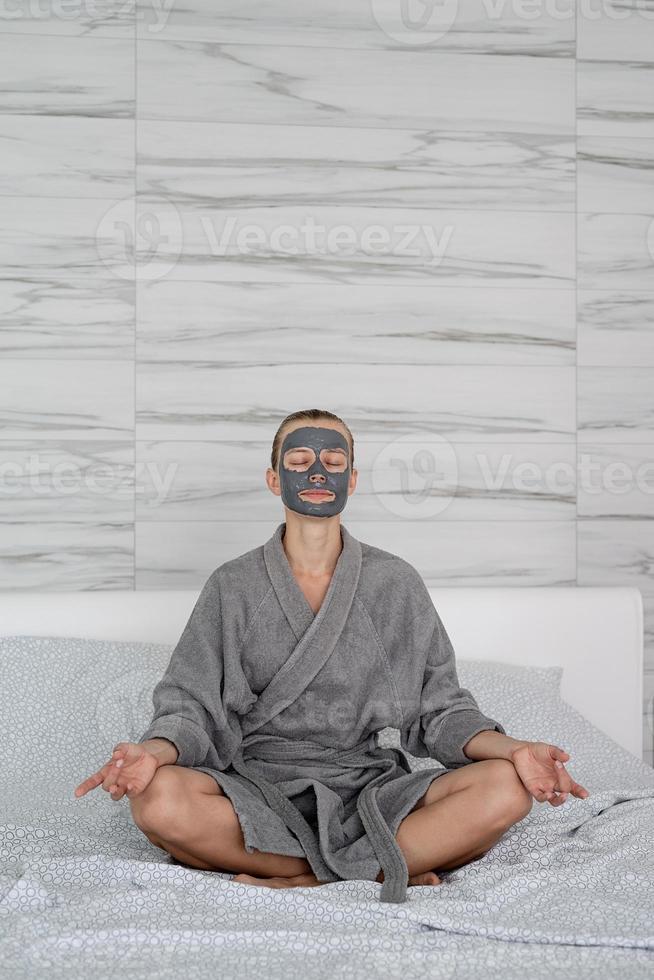 femme avec masque facial relaxant assis sur le lit photo