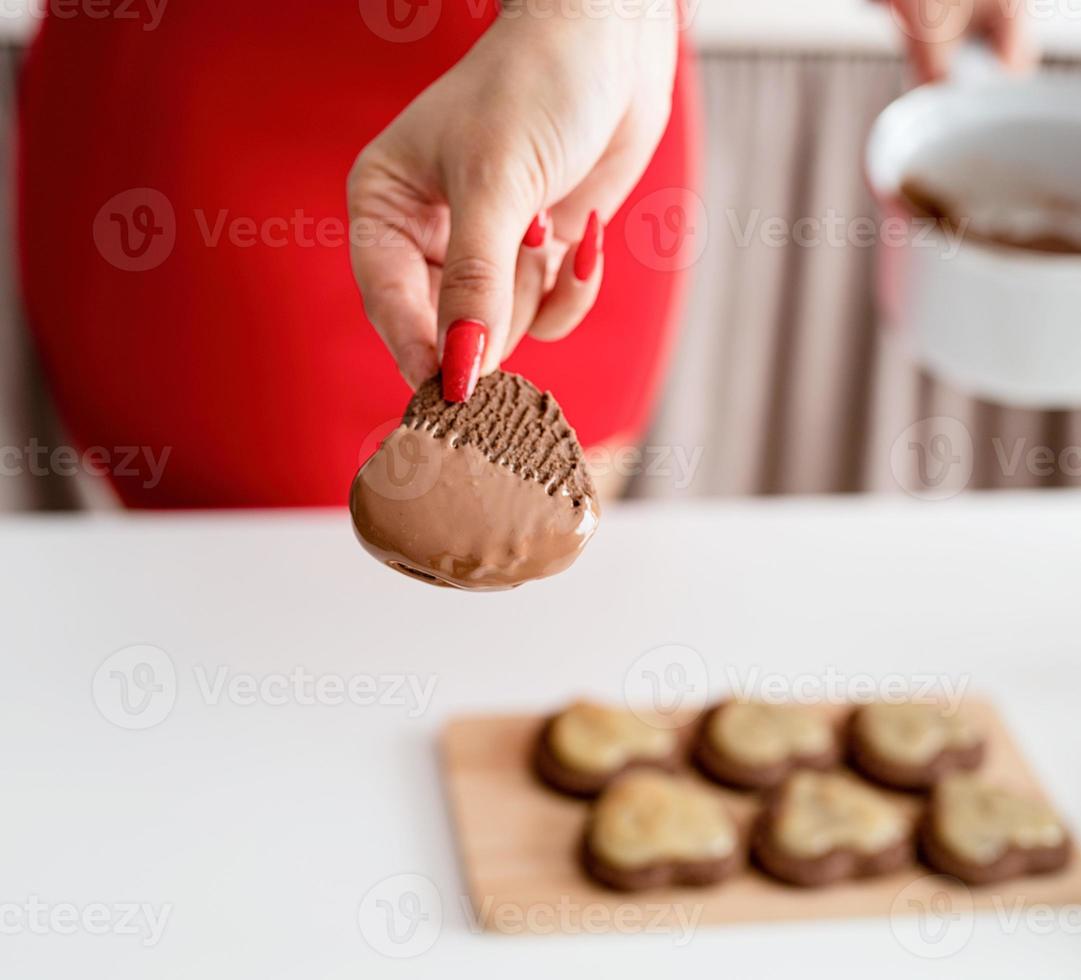 femme en robe rouge faisant des biscuits de la Saint-Valentin à la cuisine photo