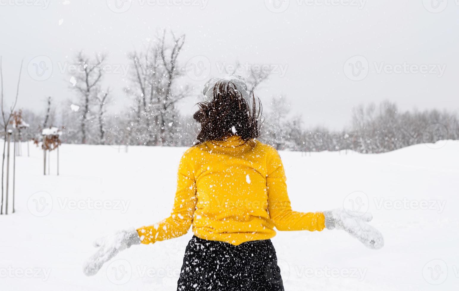 Jeune femme brune jouant avec de la neige dans le parc photo