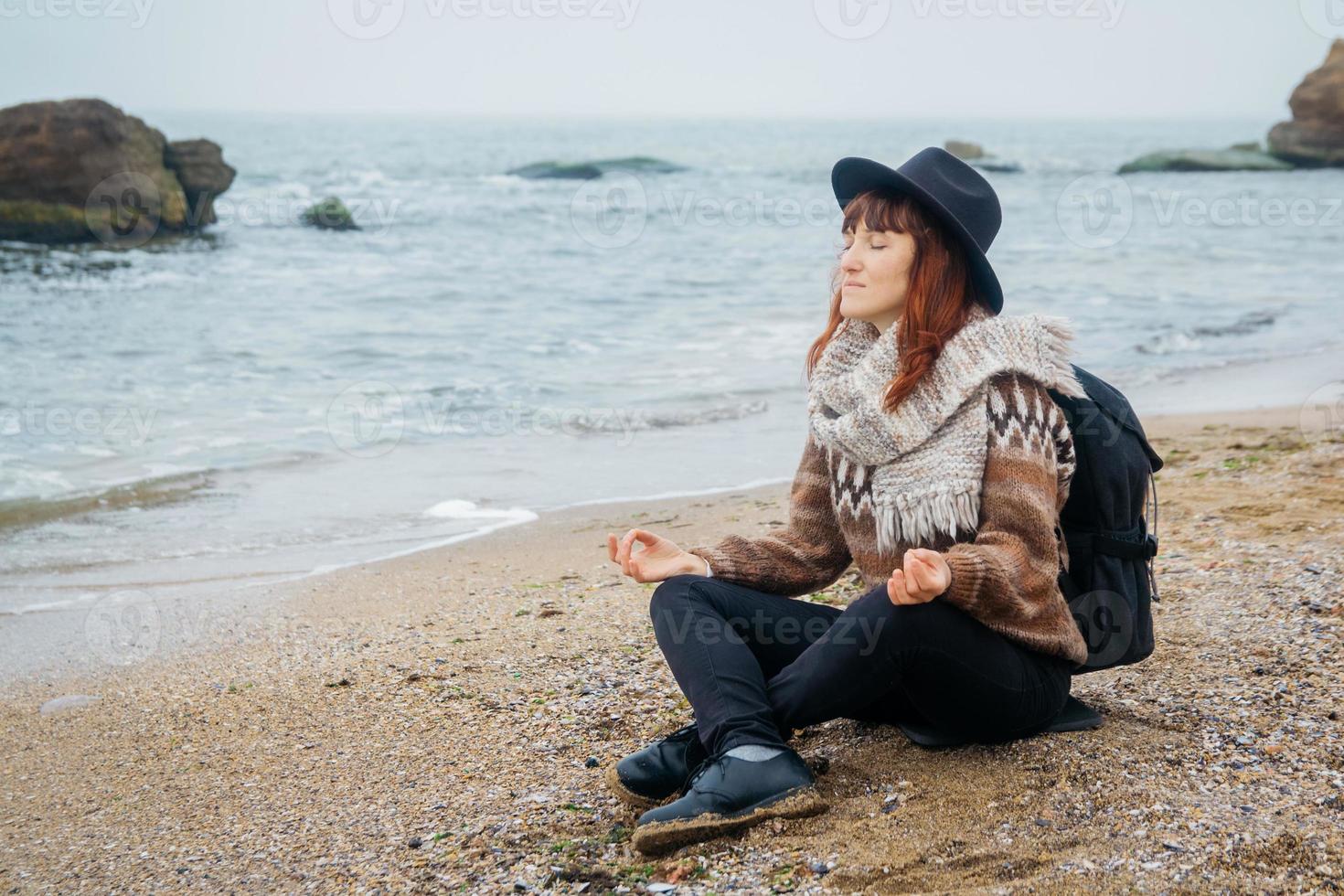 femme dans un chapeau avec un sac à dos sur fond de mer et de rochers photo