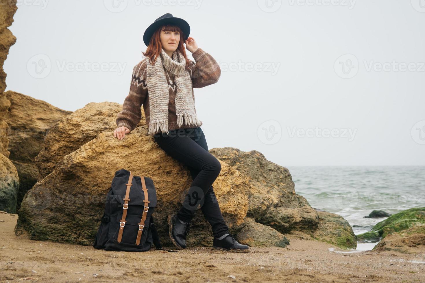 femme dans un chapeau avec un sac à dos sur fond de mer et de rochers photo