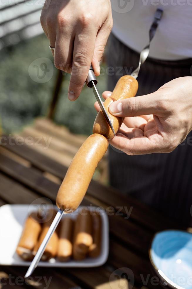 Jeune homme grillant des saucisses sur des brochettes, homme grillant de la viande à l'extérieur photo