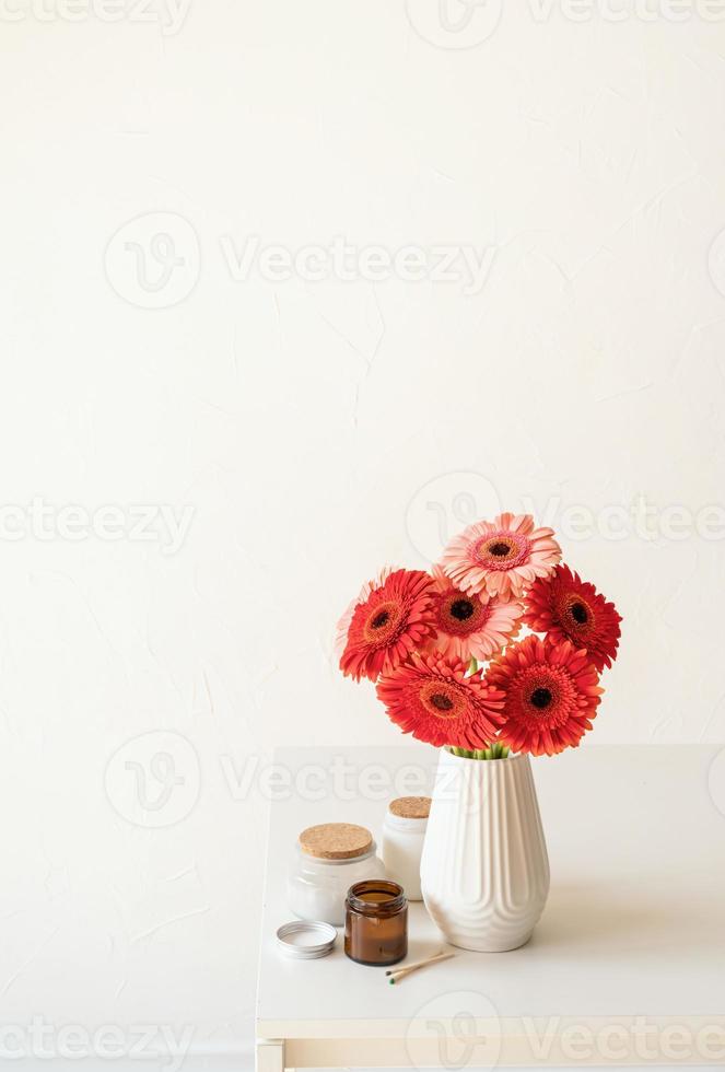 marguerites gerbera lumineuses dans un vase blanc sur une table de cuisine, style minimaliste photo