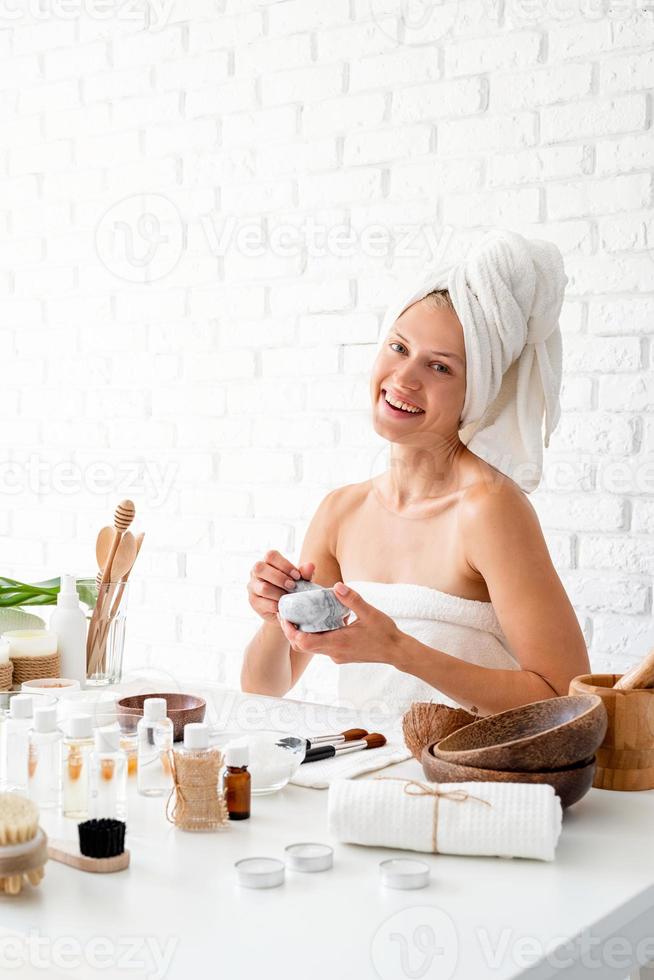 jeune femme appliquant un masque facial spa sur son visage avec un pinceau cosmétique photo