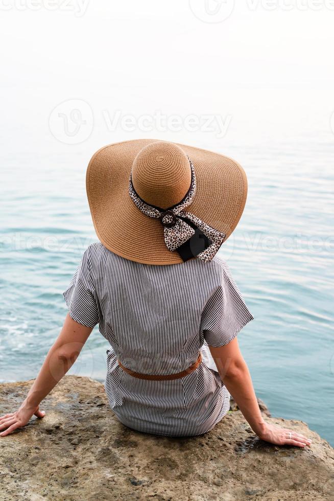 femme assise au bord de la mer vue arrière photo