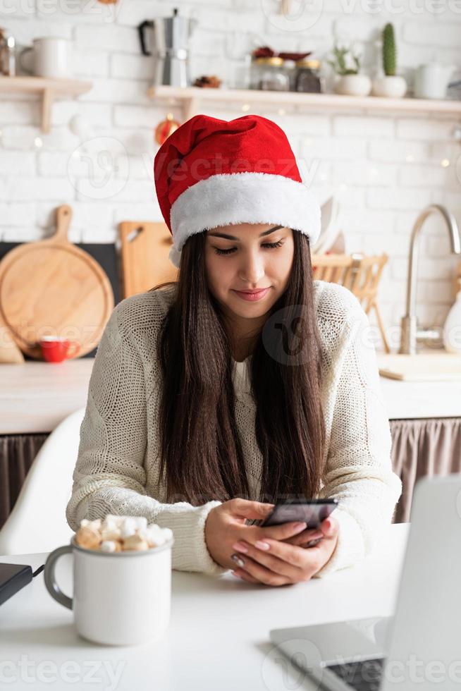 femme en bonnet de noel discutant avec des amis à l'aide de son téléphone portable photo