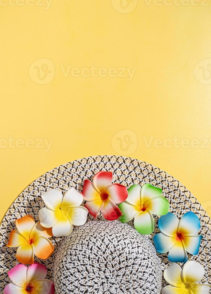 chapeau d'été avec des fleurs de plumeria sur fond jaune photo