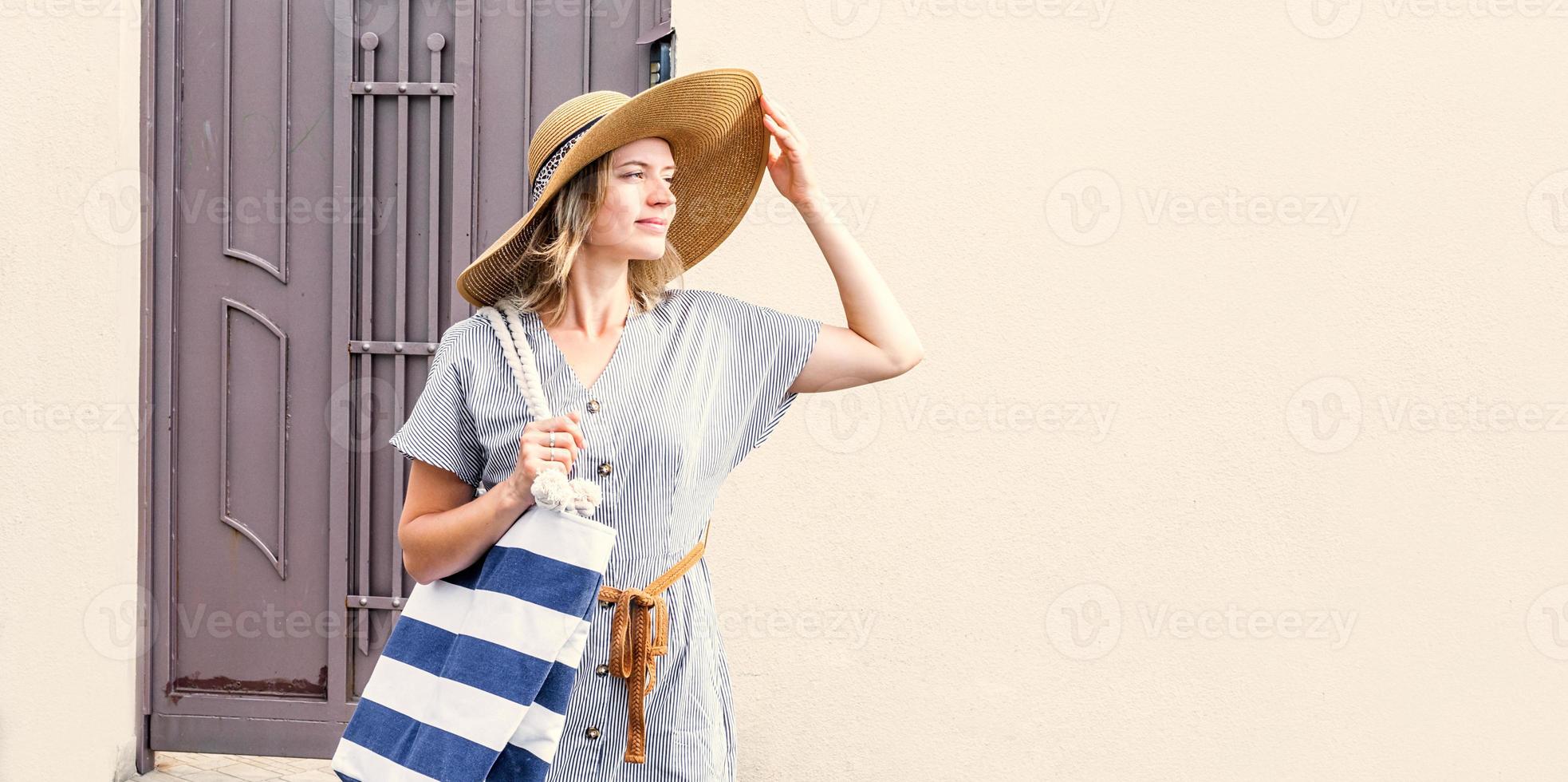 femme avec chapeau debout à l'extérieur dans la rue à la recherche du soleil photo