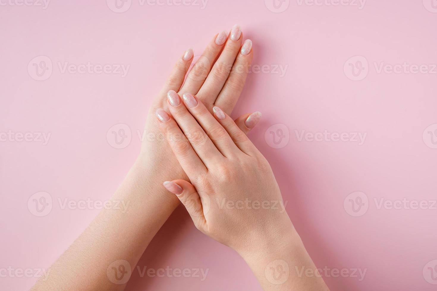 belles mains féminines sur fond rose. concept de spa et de soins du corps. photo