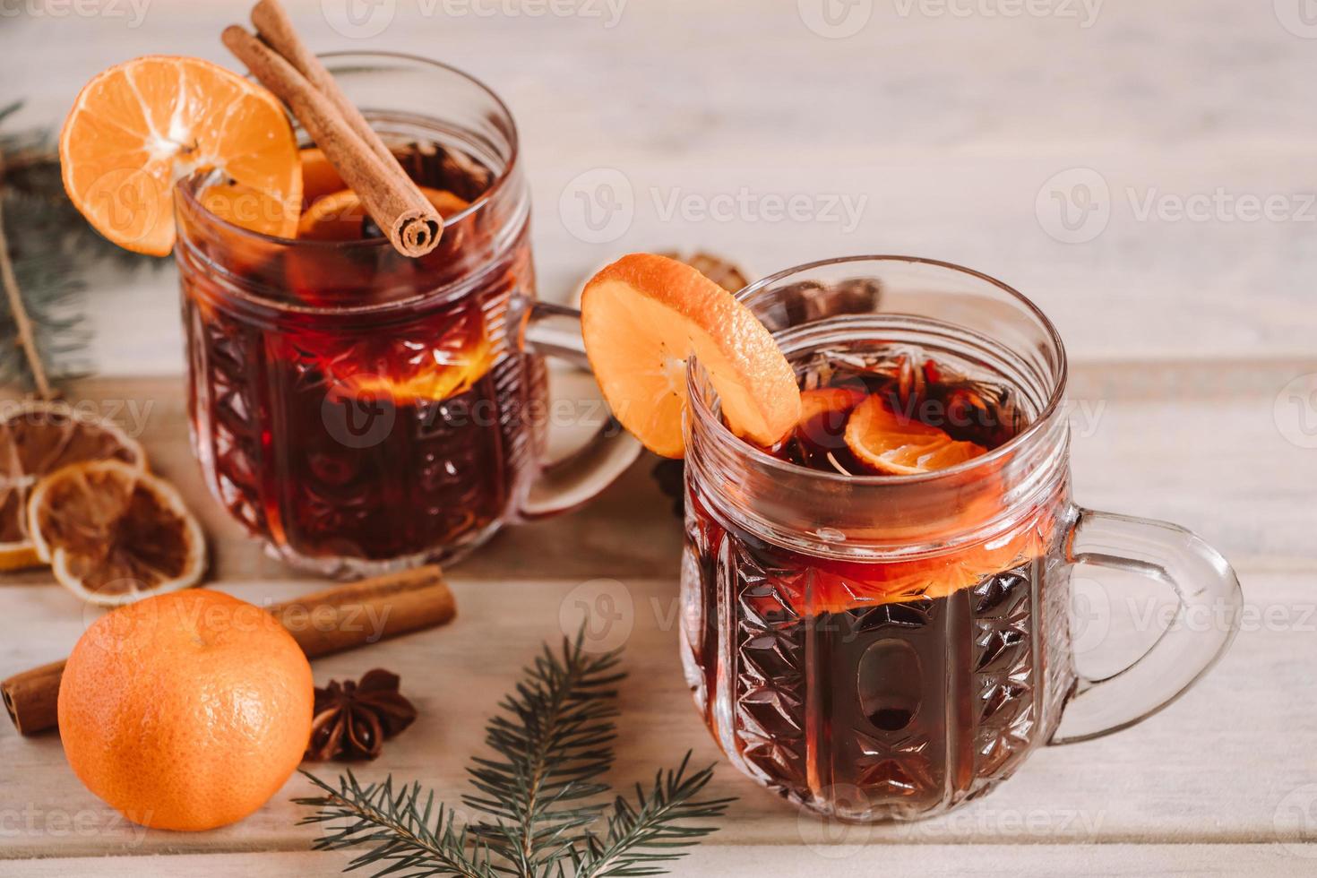 vin chaud aux épices dans une tasse en verre sur fond de bois. photo