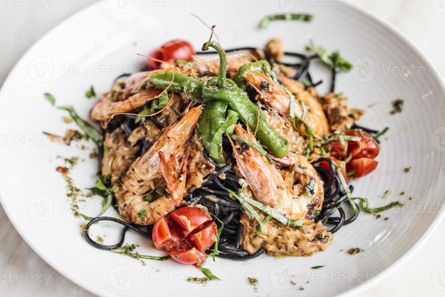 Cuisine gastronomique crevettes grillées et légumes sur repas de pâtes à l'encre de seiche noire photo