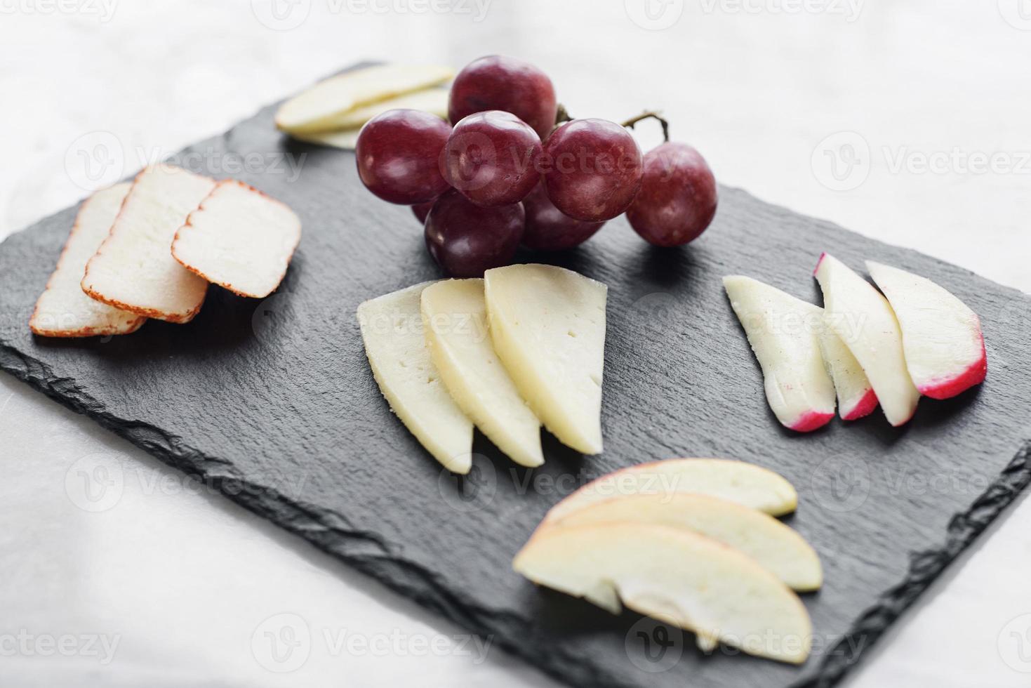 entrée gastronomique de tapas au plateau de fromages mélangés avec collation aux pommes et aux raisins photo