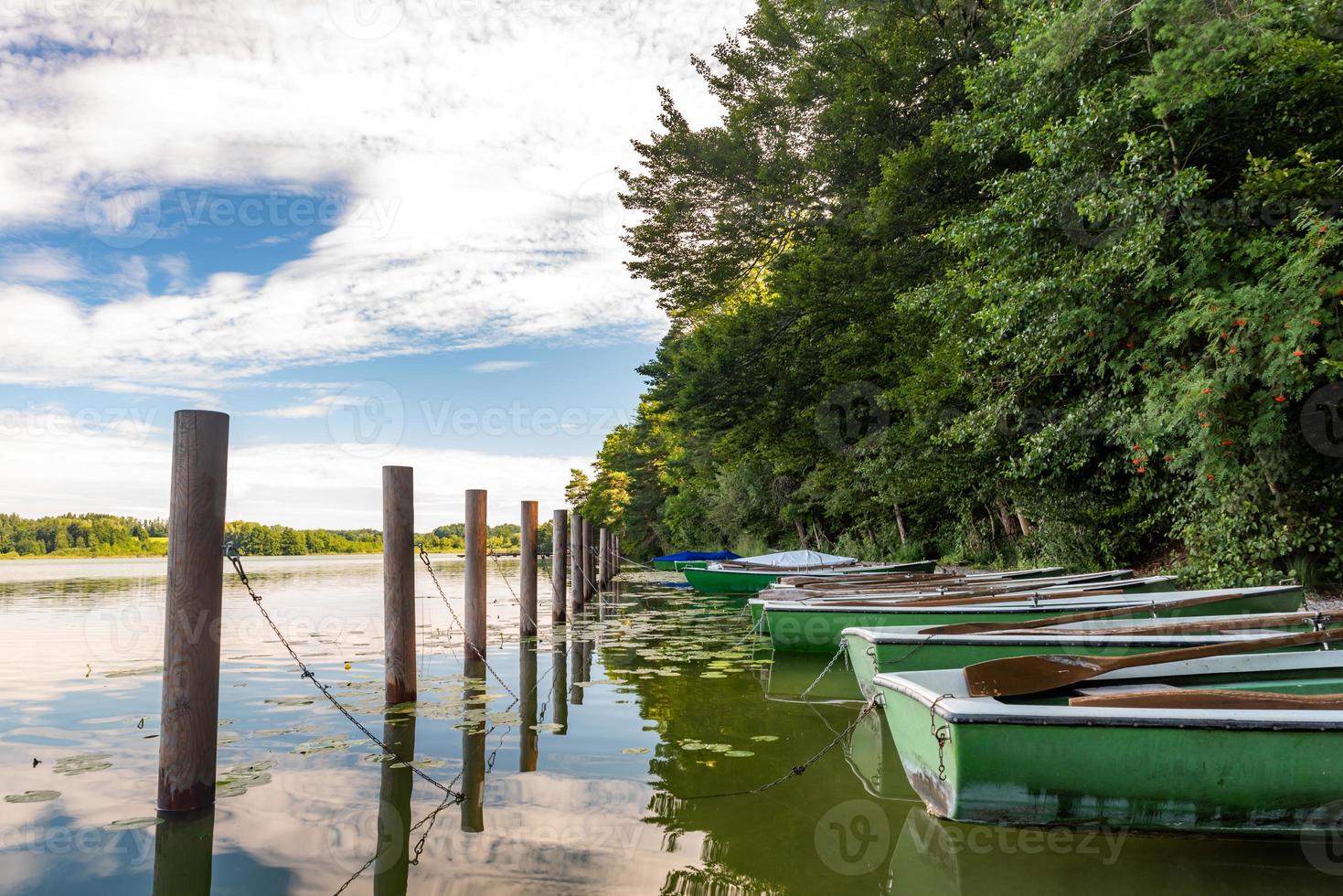 des bateaux à rames se trouvent sur la rive d'un lac en Bavière avec une forêt photo