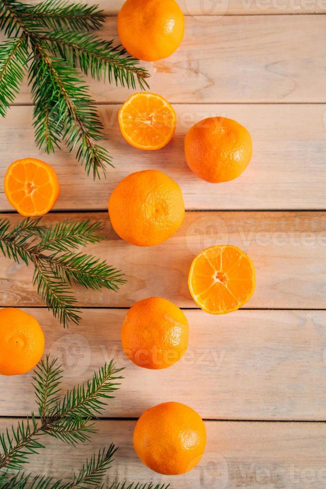 cadre fait de branches de sapin et de mandarines sur fond de bois. photo