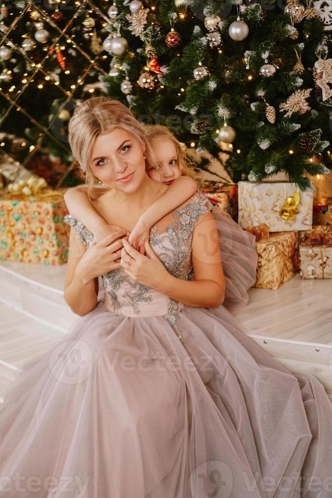 fille étreignant sa mère alors qu'elle était assise à l'arbre de Noël photo