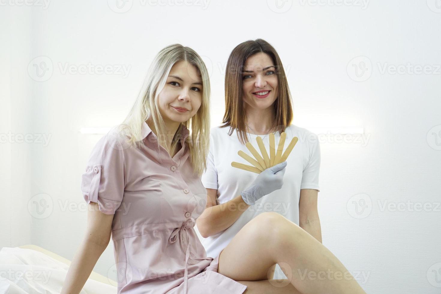 Le maître féminin de l'épilation ou du sucre tient une spatule en bois photo