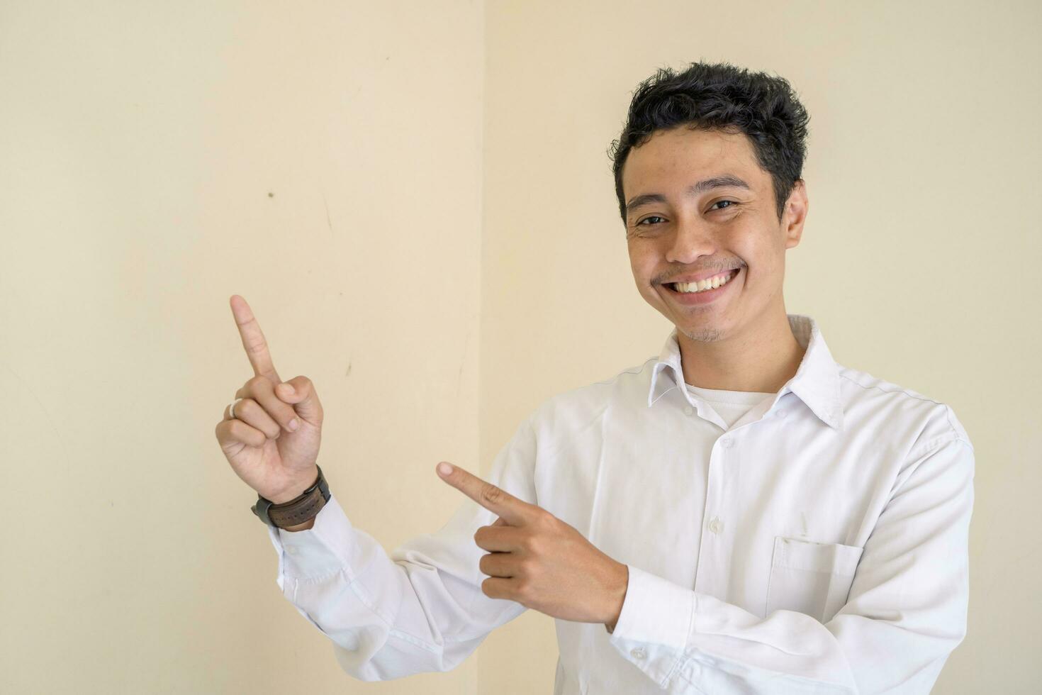 Jeune indonésien frisé homme porter blanc vêtements avec la vignette pose. photo