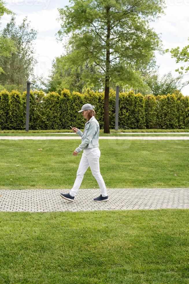 femme à l'extérieur textos sur son téléphone portable, marchant dans le parc photo