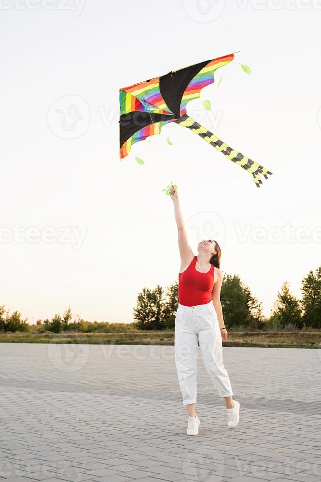 Jeune femme faisant voler un cerf-volant dans un parc public au coucher du soleil photo