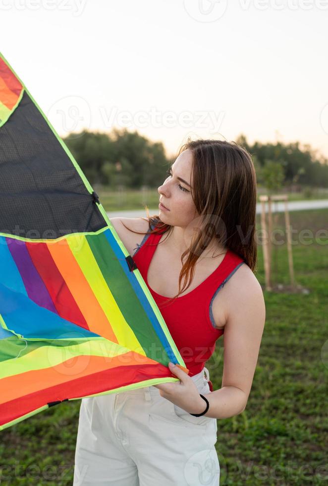 Jeune femme faisant voler un cerf-volant dans un parc public au coucher du soleil photo