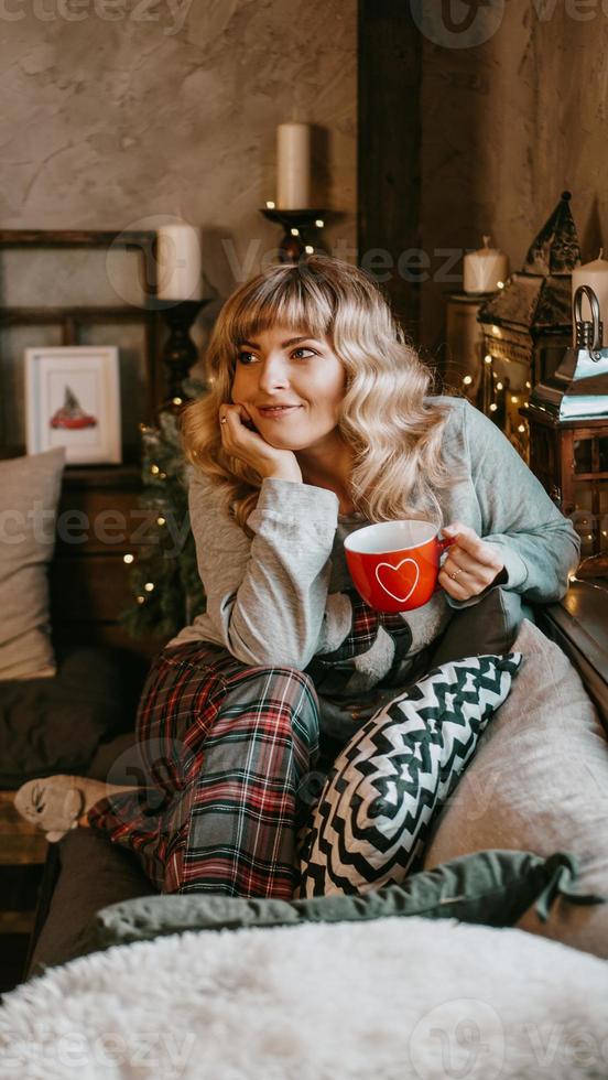 jeune femme avec une tasse de thé dans un intérieur confortable de noël photo