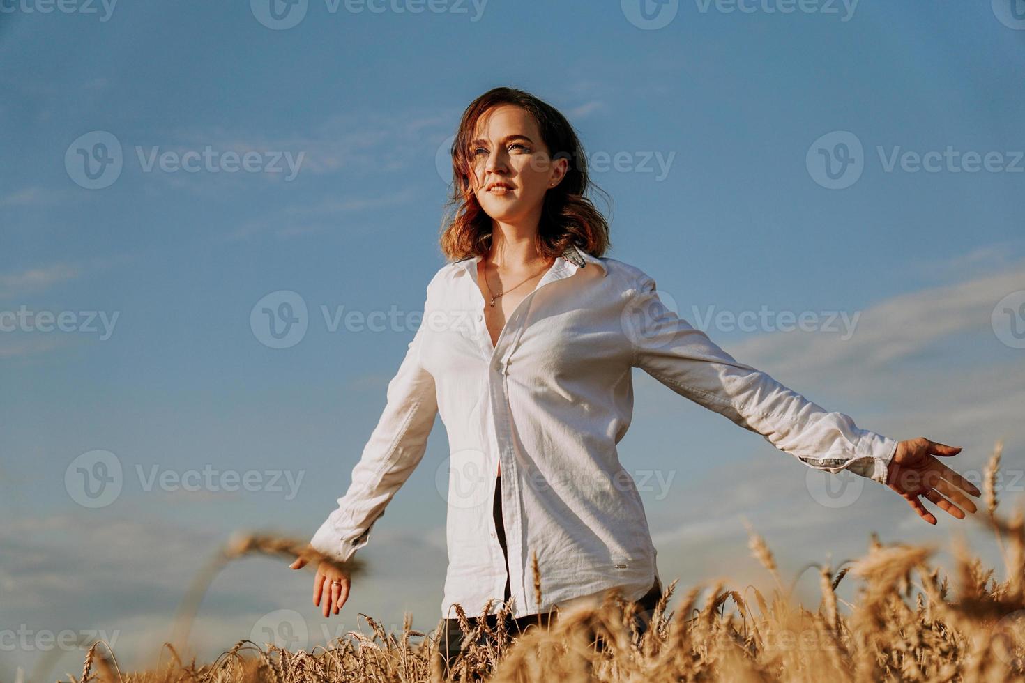 heureuse jeune femme en chemise blanche dans un champ de blé. journée ensoleillée. photo