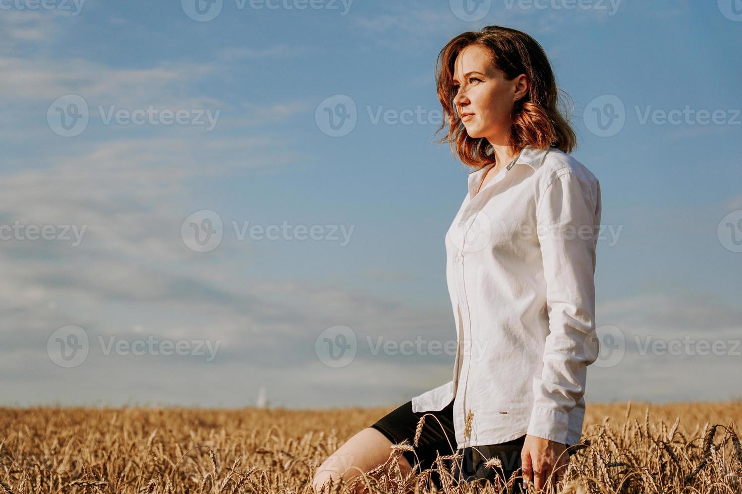 heureuse jeune femme en chemise blanche dans un champ de blé. journée ensoleillée. photo