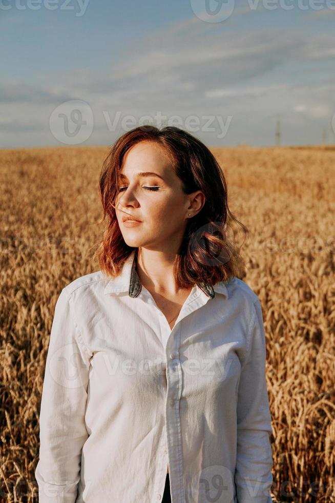 fille rousse dans une chemise blanche. elle dans un champ de seigle par une journée ensoleillée photo