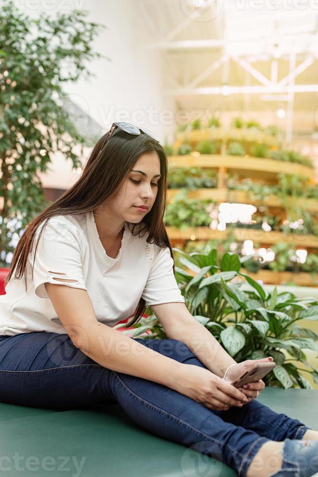 femme assise sur le canapé dans le centre commercial, regardant le téléphone photo