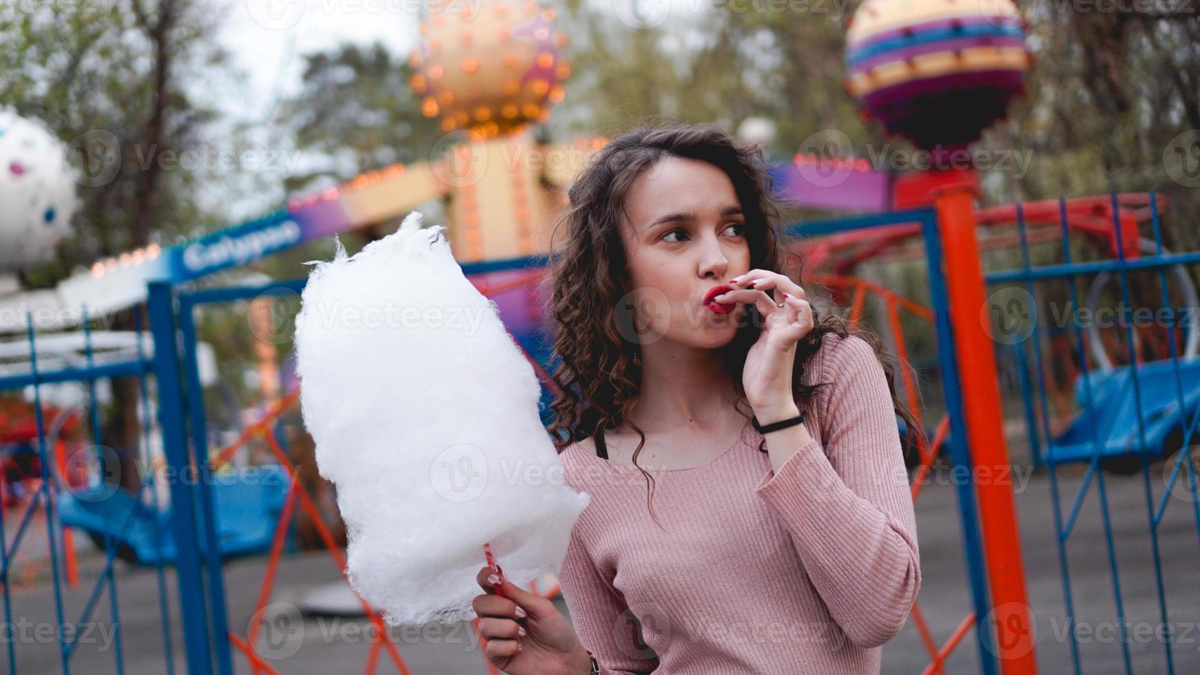 fille excitée souriante tenant une barbe à papa au parc d'attractions photo