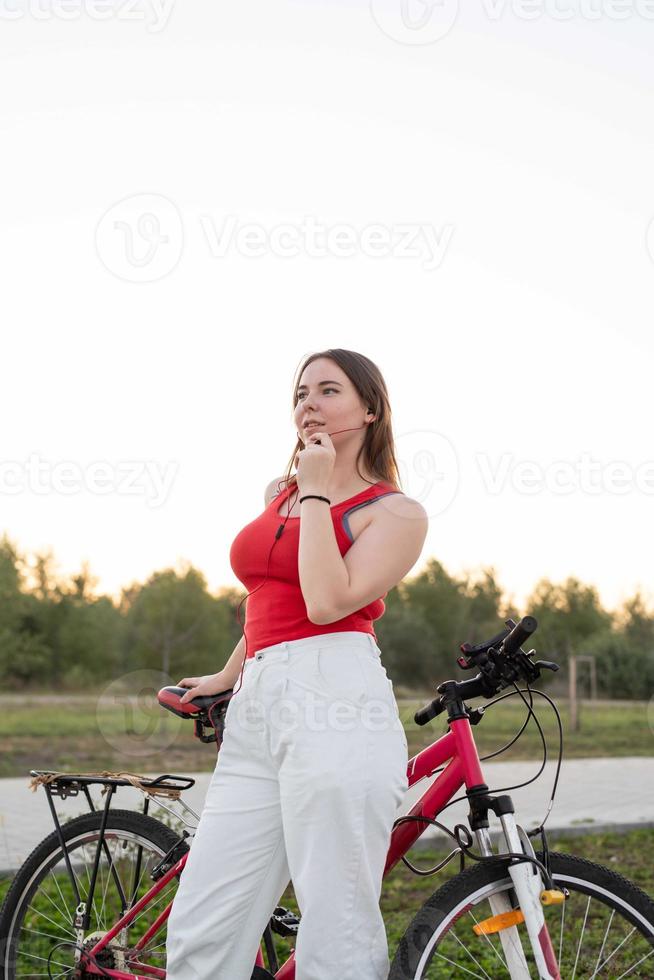 fille avec son vélo écoutant de la musique dans le parc au coucher du soleil photo