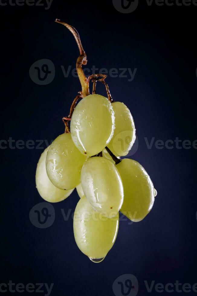 une petit bouquet de mûr vert les raisins sur une noir Contexte. photo