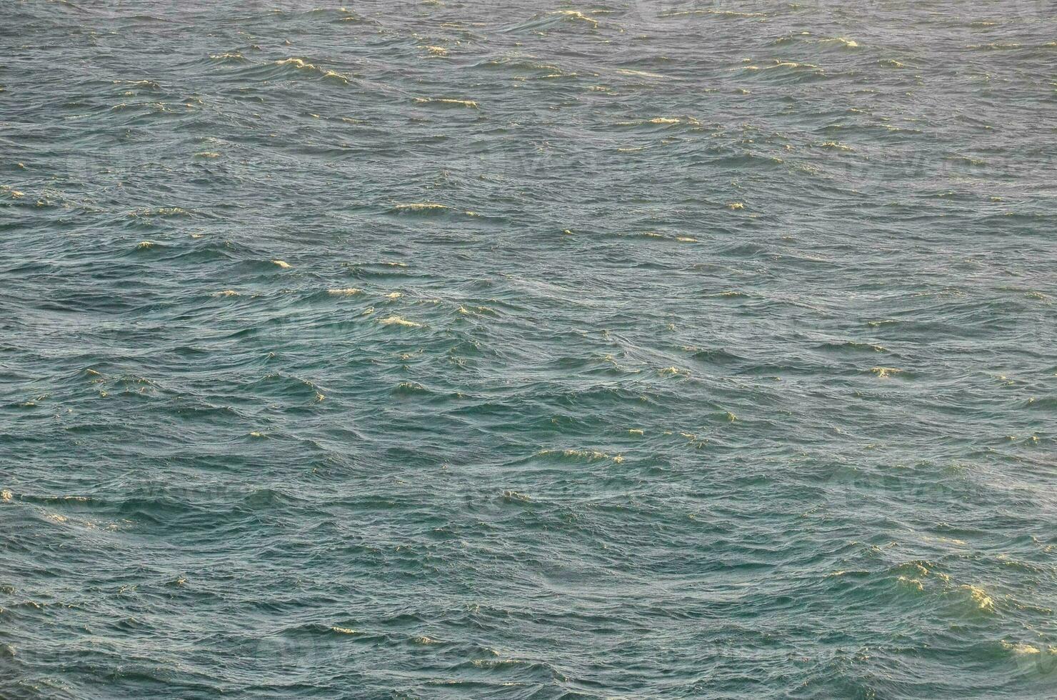 une grand corps de l'eau avec vagues et une bateau dans le milieu photo