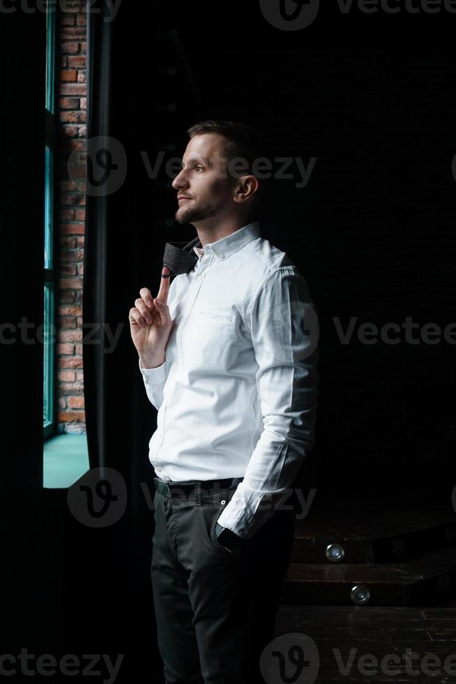 vue de profil d'un jeune homme d'affaires debout près de la fenêtre photo