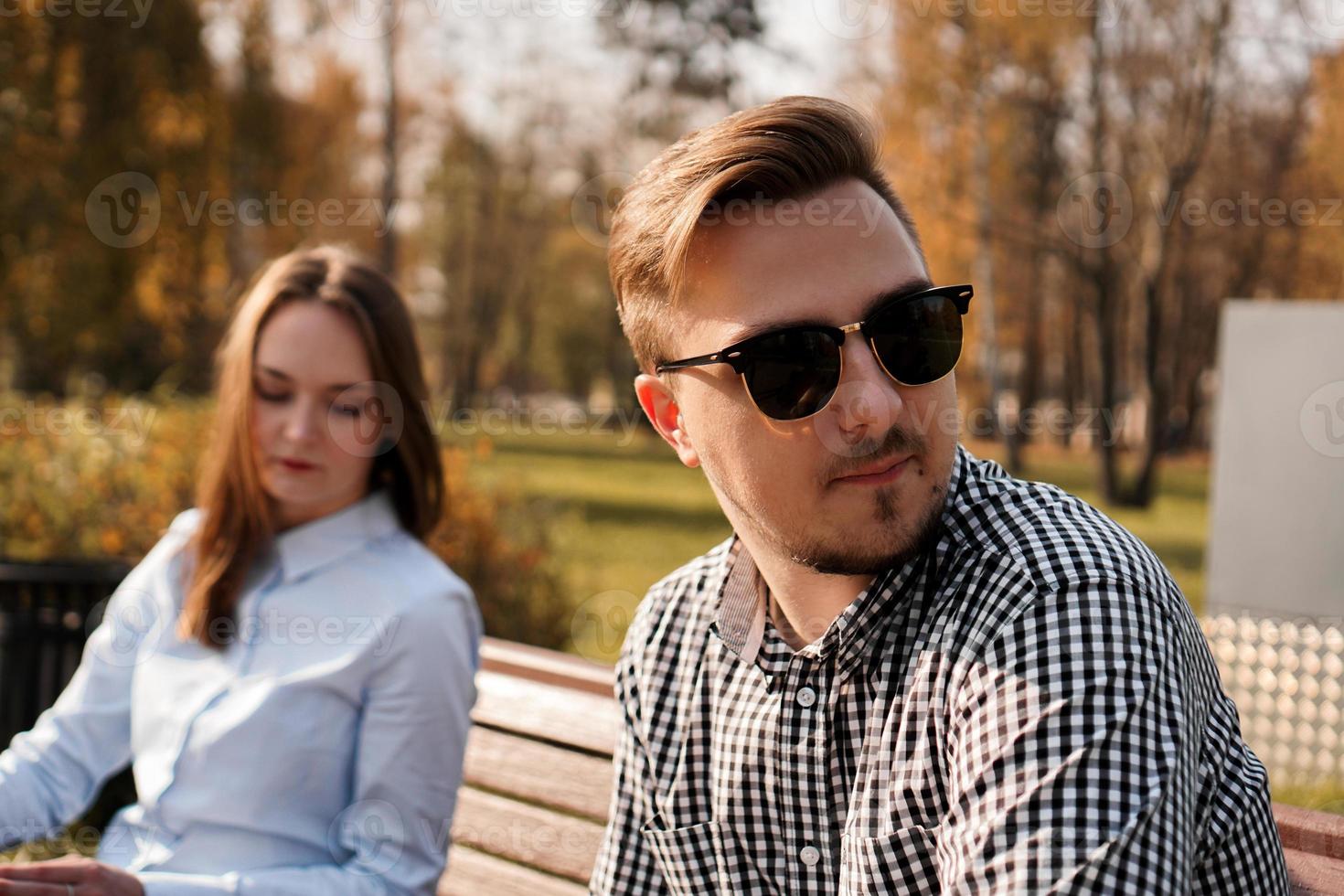 Jeune couple en querelle assis sur un banc dans le parc photo