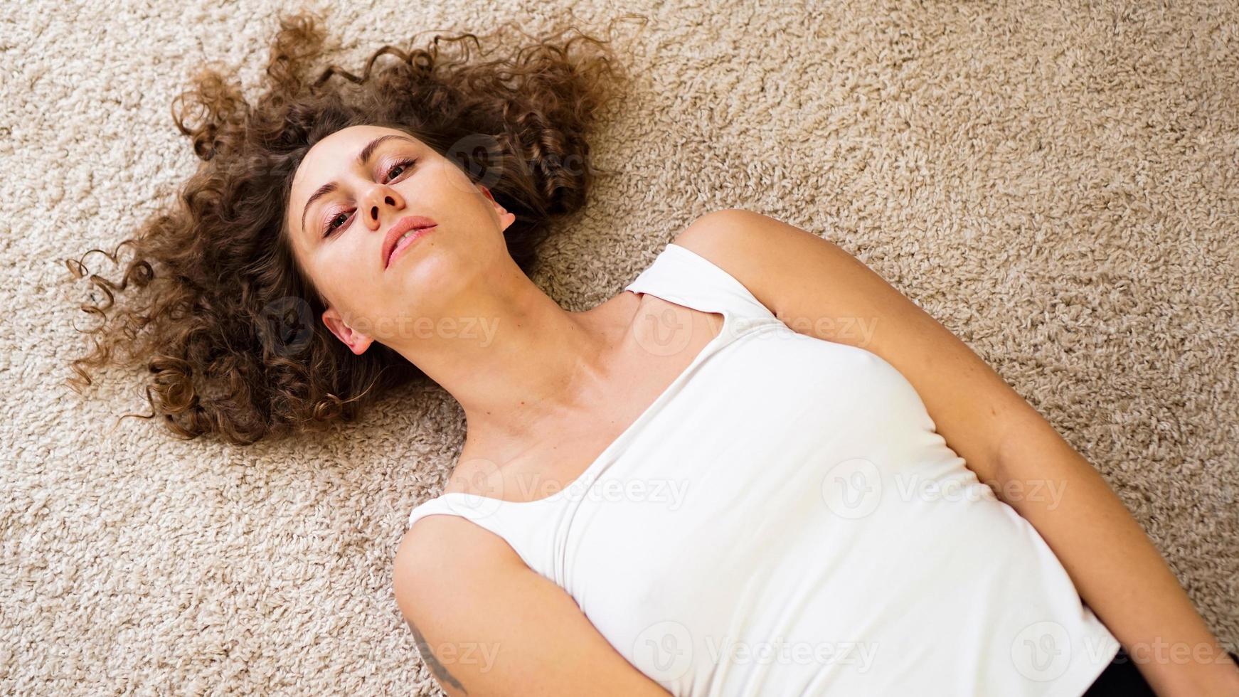 femme allongée sur un tapis, heureuse jeune fille adulte allongée sur le sol photo