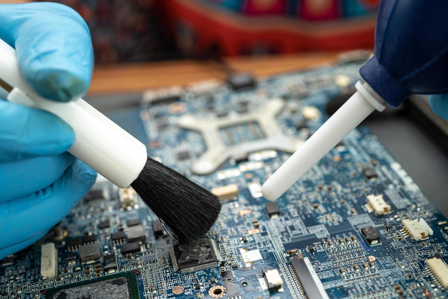 le technicien utilise une brosse pour nettoyer la poussière dans l'ordinateur de la carte de circuit imprimé. photo