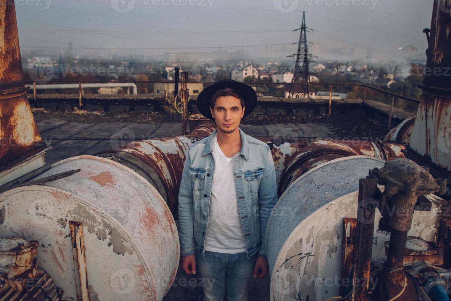 homme avec un chapeau portant une chemise blanche et un jean sur fond de ville photo