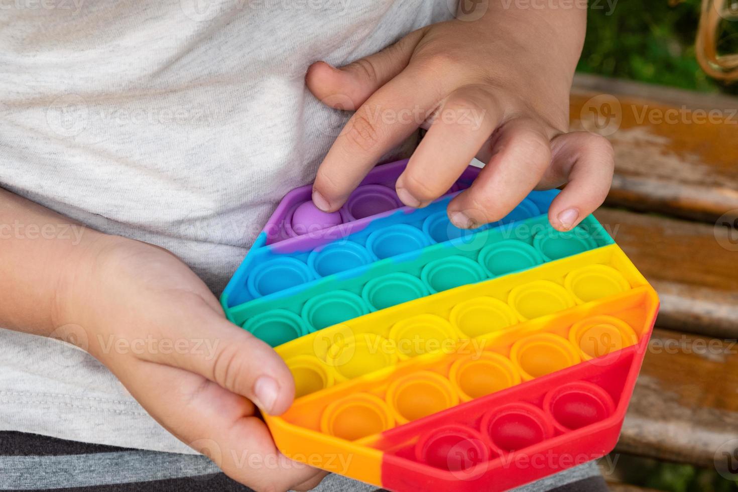 jeu d'enfant avec une presse à doigt pop coloré il remue le jouet. photo