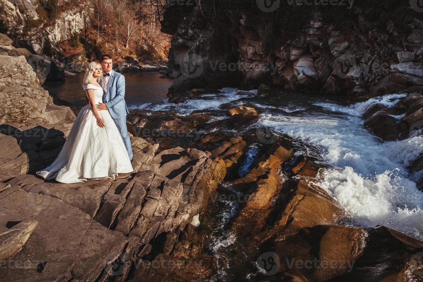 couple marié embrassant avec un fond de montagne et de rivière photo