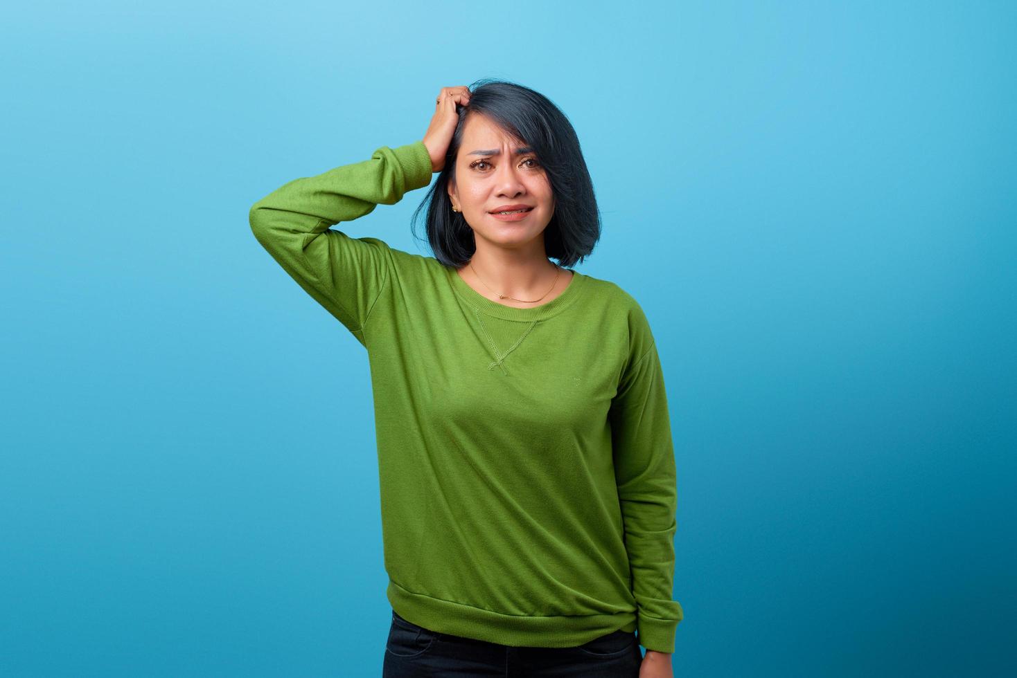 femme asiatique touchant sa tête et exprimant son inquiétude sur fond bleu photo