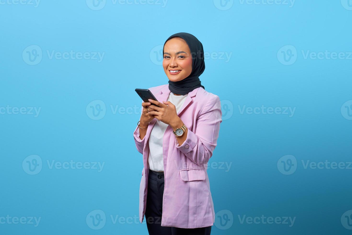 une femme asiatique joyeuse tient un téléphone portable et levant les yeux photo