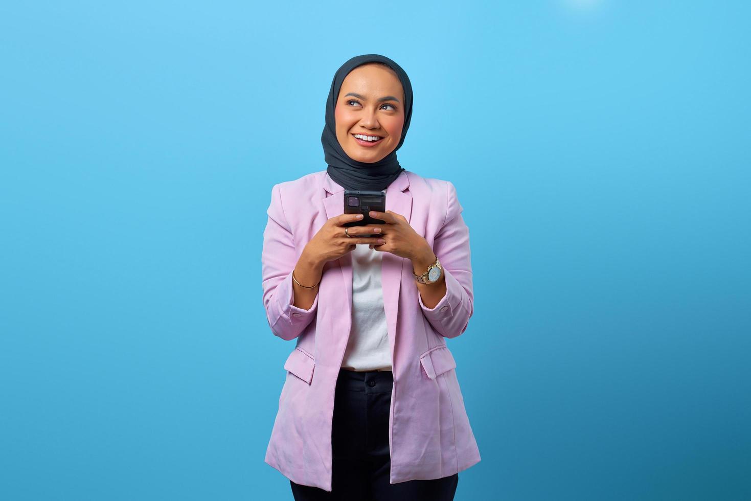 une femme asiatique joyeuse tient un téléphone portable et levant les yeux photo