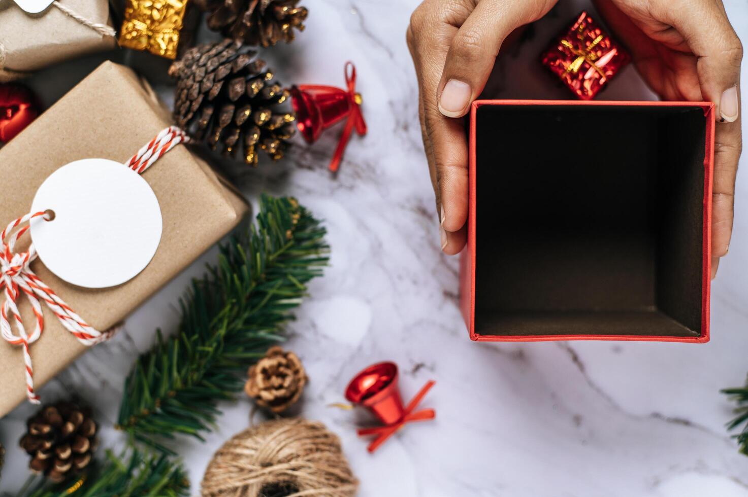 une main tenant une boîte-cadeau noire sur un sol en ciment blanc photo