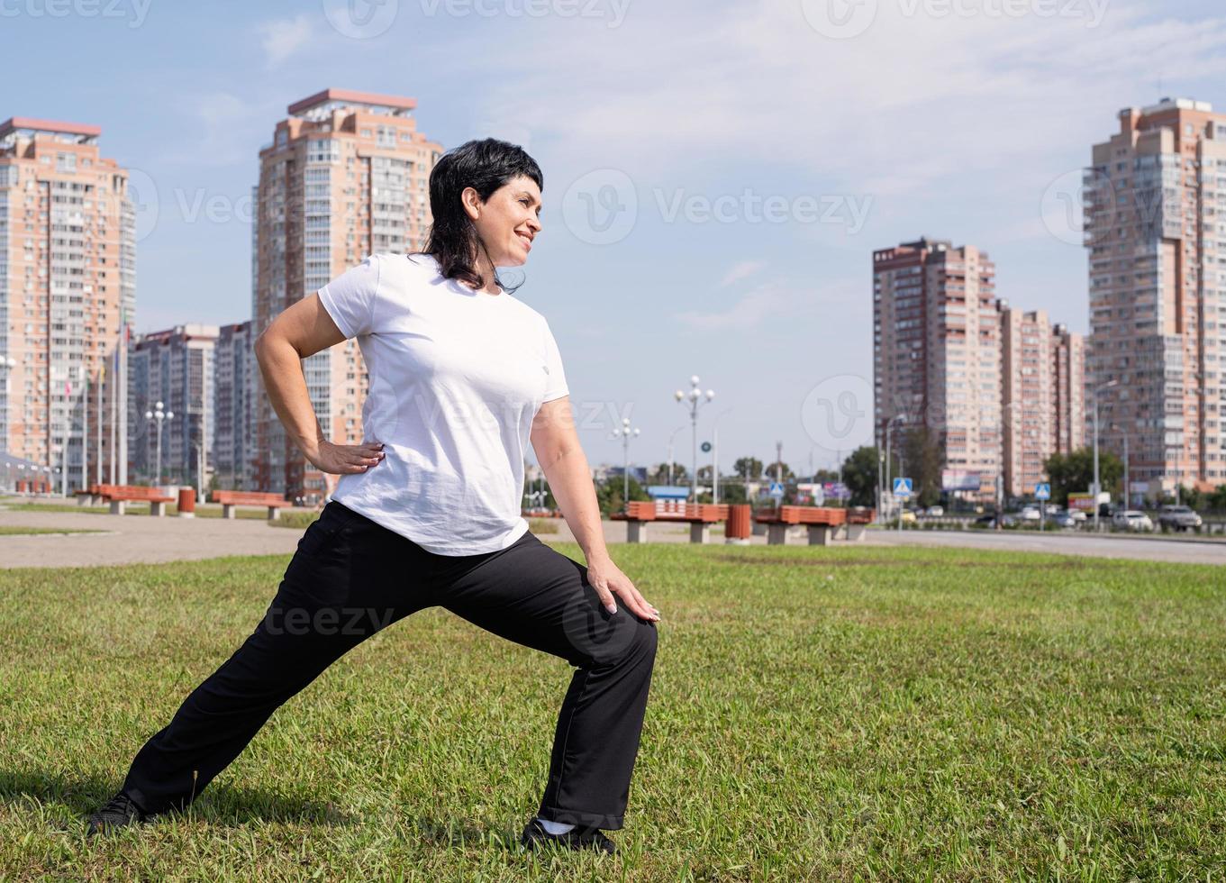 smiling senior woman warming stretching à l'extérieur dans le parc photo