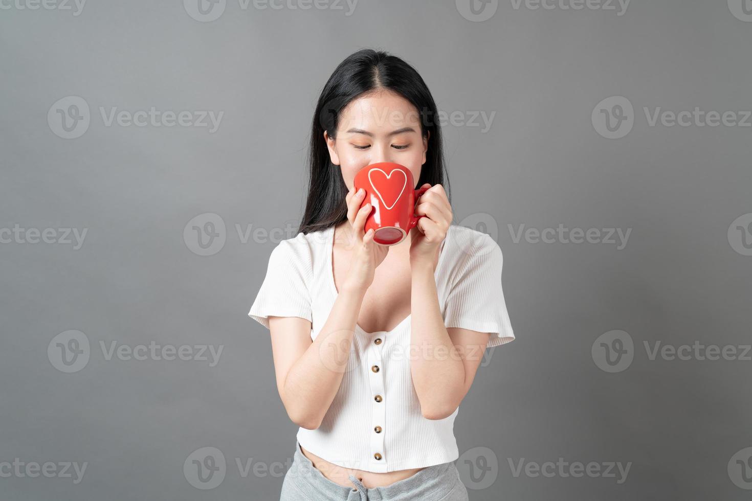 jeune femme asiatique avec un visage heureux et une main tenant une tasse de café photo