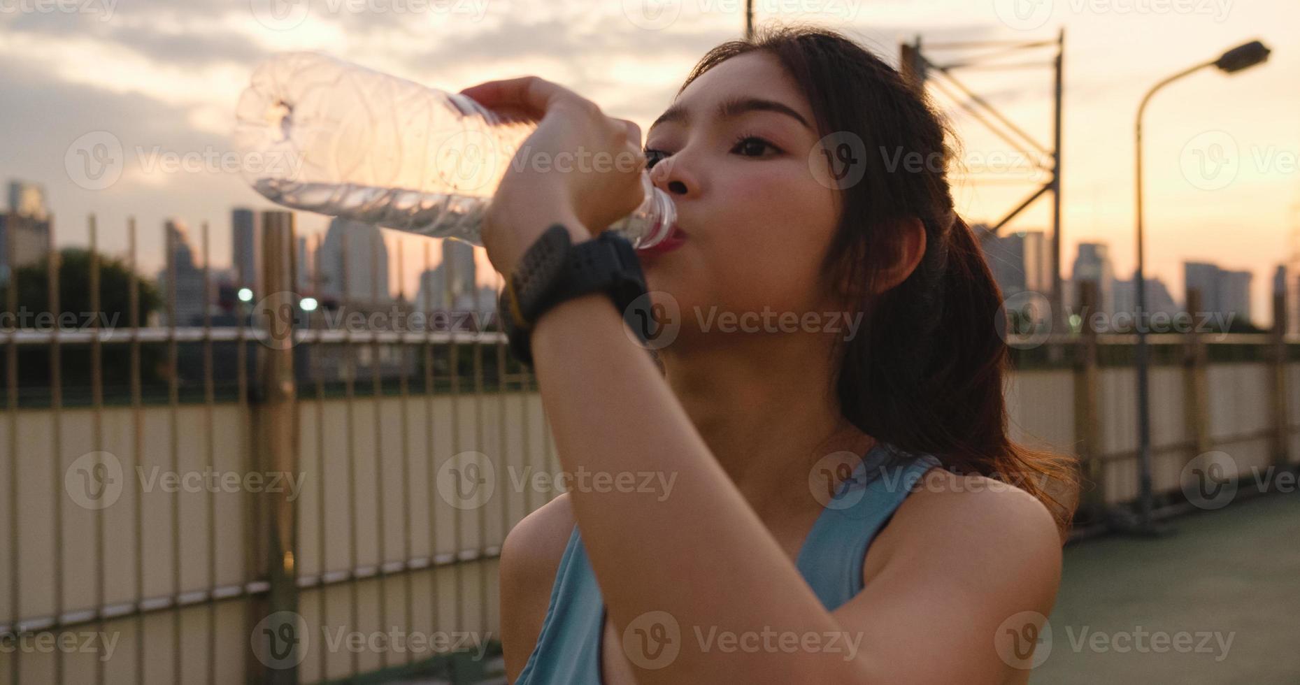 asie athlète dame exerce de l'eau potable après avoir couru en milieu urbain. photo