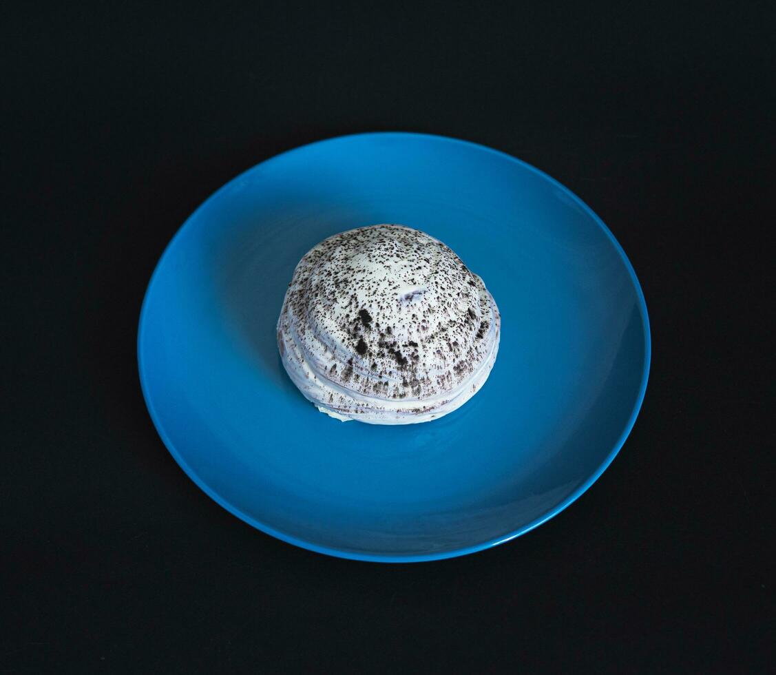 de beurre sucré chignon dans blanc Chocolat glaçage sur une bleu assiette photo