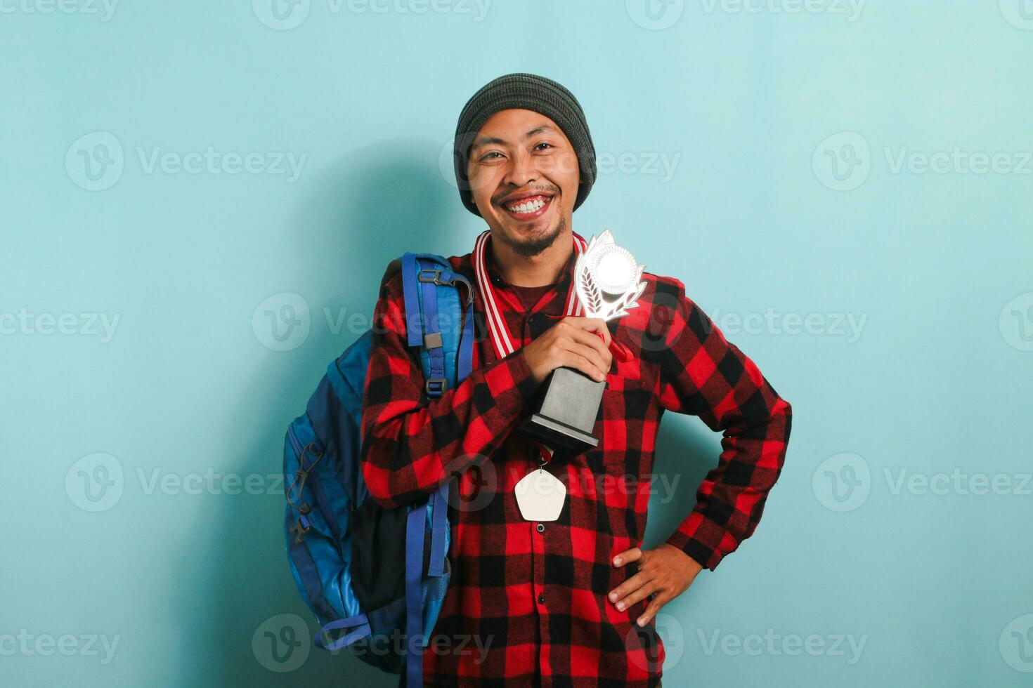 content Jeune asiatique homme étudiant montrant une médaille et trophée, isolé sur une bleu Contexte photo